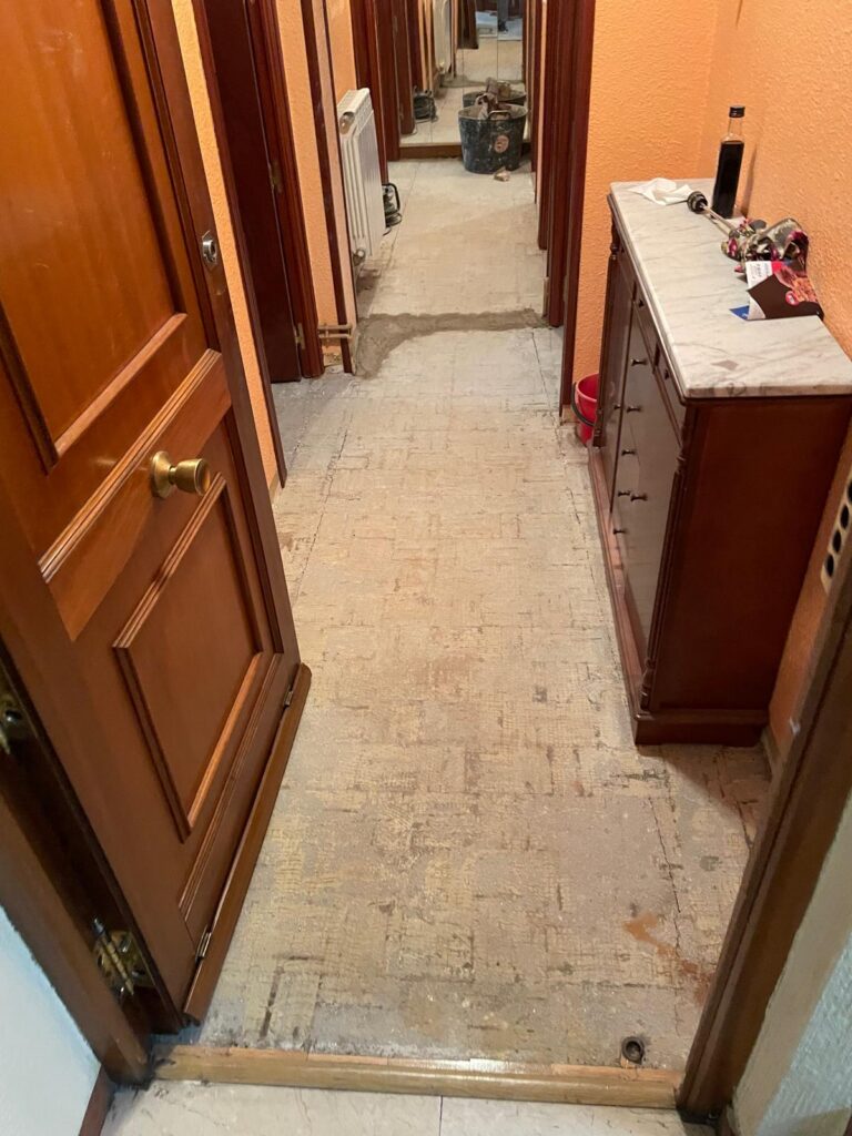 Pasillo en obra con suelo levantado antes de la reforma