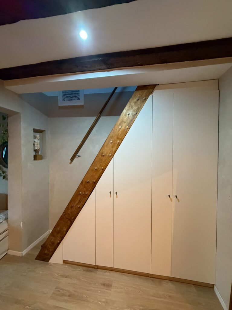 Armario empotrado blanco y escalera de madera en buhardilla reformada