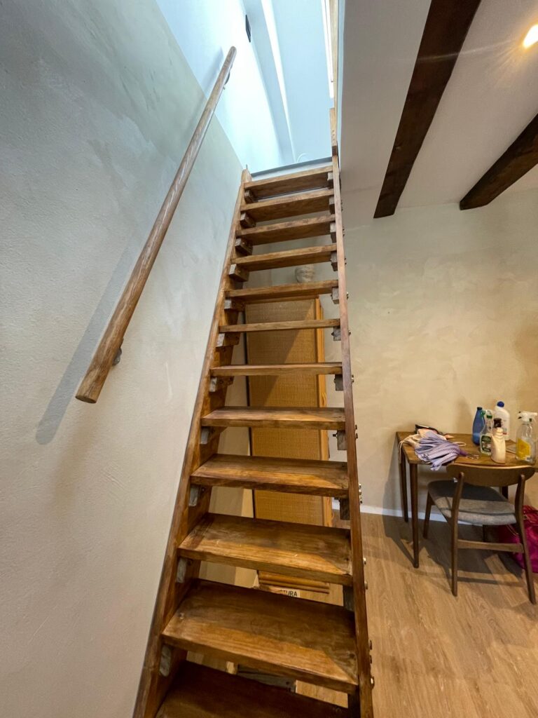 Escalera de madera a la buhardilla con vigas vistas