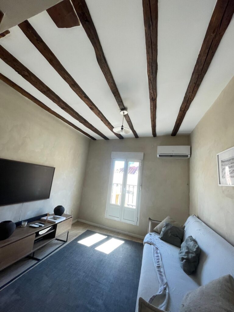 Salón reformado con vigas de madera vistas y suelo nuevo