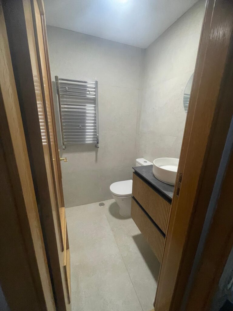 Baño reformado con mueble de lavabo de madera y radiador toallero