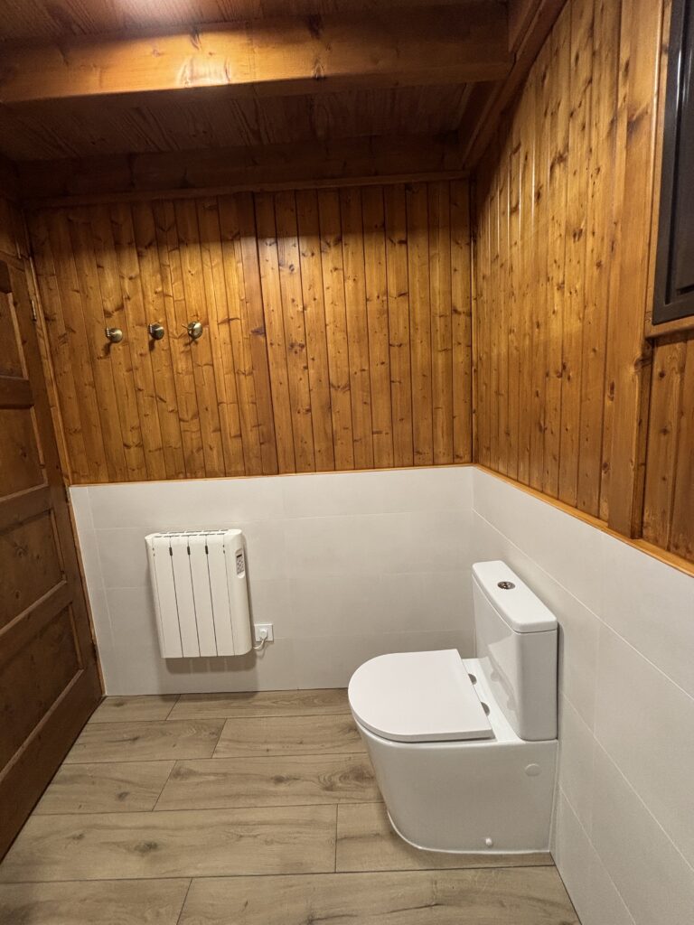 Baño abuhardillado reformado con techo de madera, inodoro suspendido y radiador